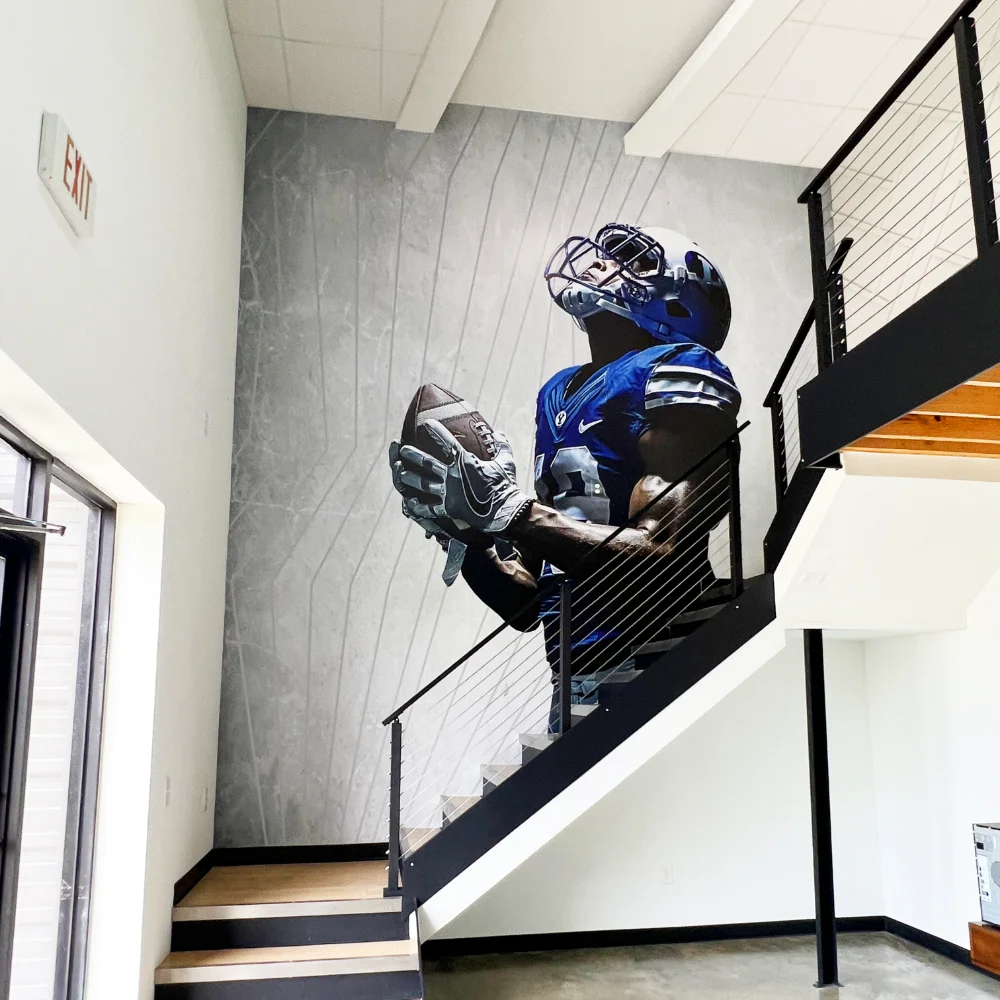 Branded environment by Uptimize: custom vinyl wall graphic of a larger-than-life football player in a two-story stairwell.